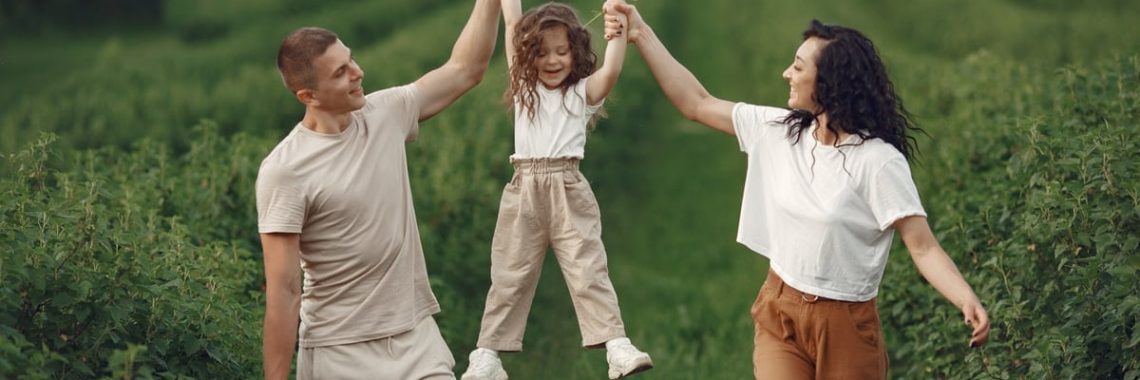 Joyful family moment in a green field during summer, capturing love and playfulness.
